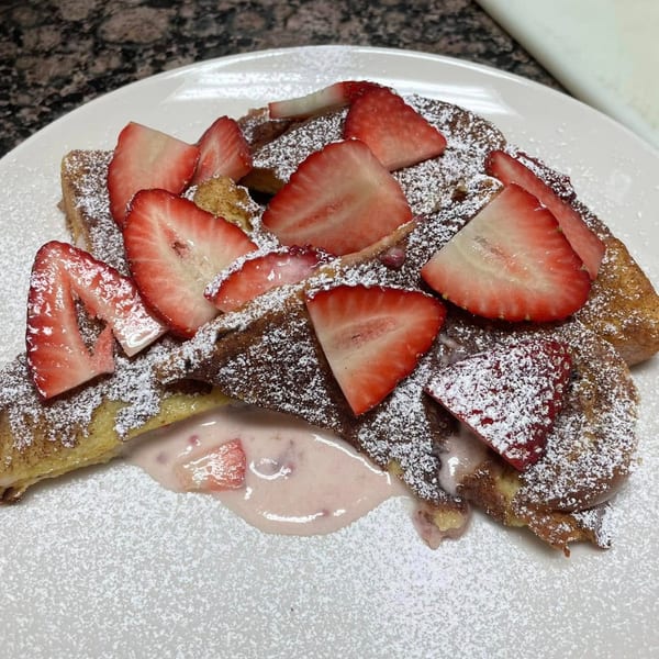 Courthouse Cafe's French toast topped with powdered sugar, fresh strawberries, and strawberry cream.