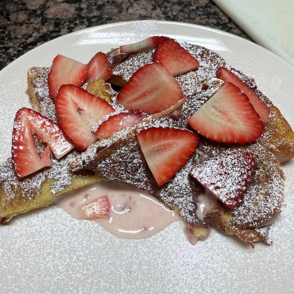 Courthouse Cafe's French toast topped with powdered sugar, fresh strawberries, and strawberry cream.