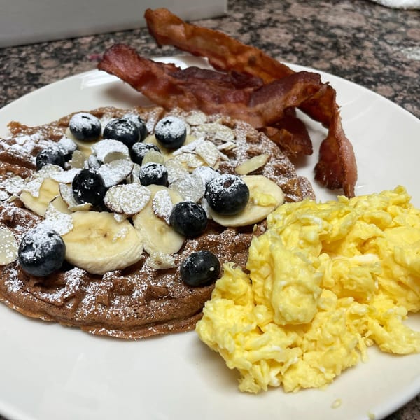 Courthouse Cafe's breakfast plate with a waffle, blueberries, bananas, almonds, scrambled eggs, and bacon.